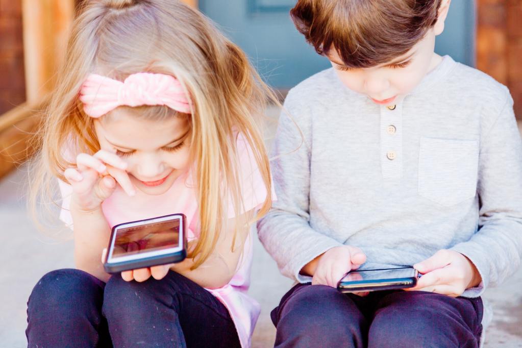 two kids playing on phones