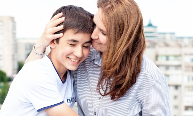 A mom embraces her teenaged son.