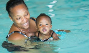 An adult teaching a baby how to swim.