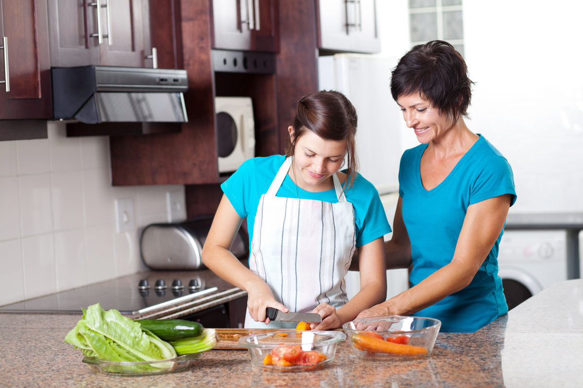 Teen girls making a meal with mom