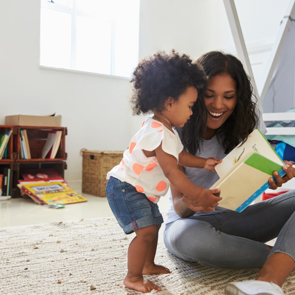 Toddler reading book with her mom
