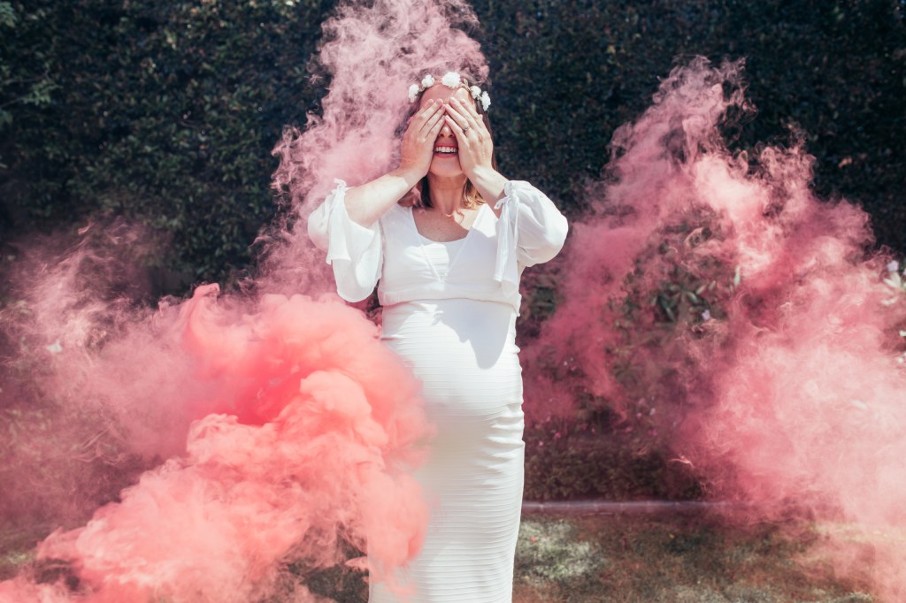 Pregnant female standing in pink smoke