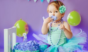 Baby girl enjoying her smash cake on her first birthday