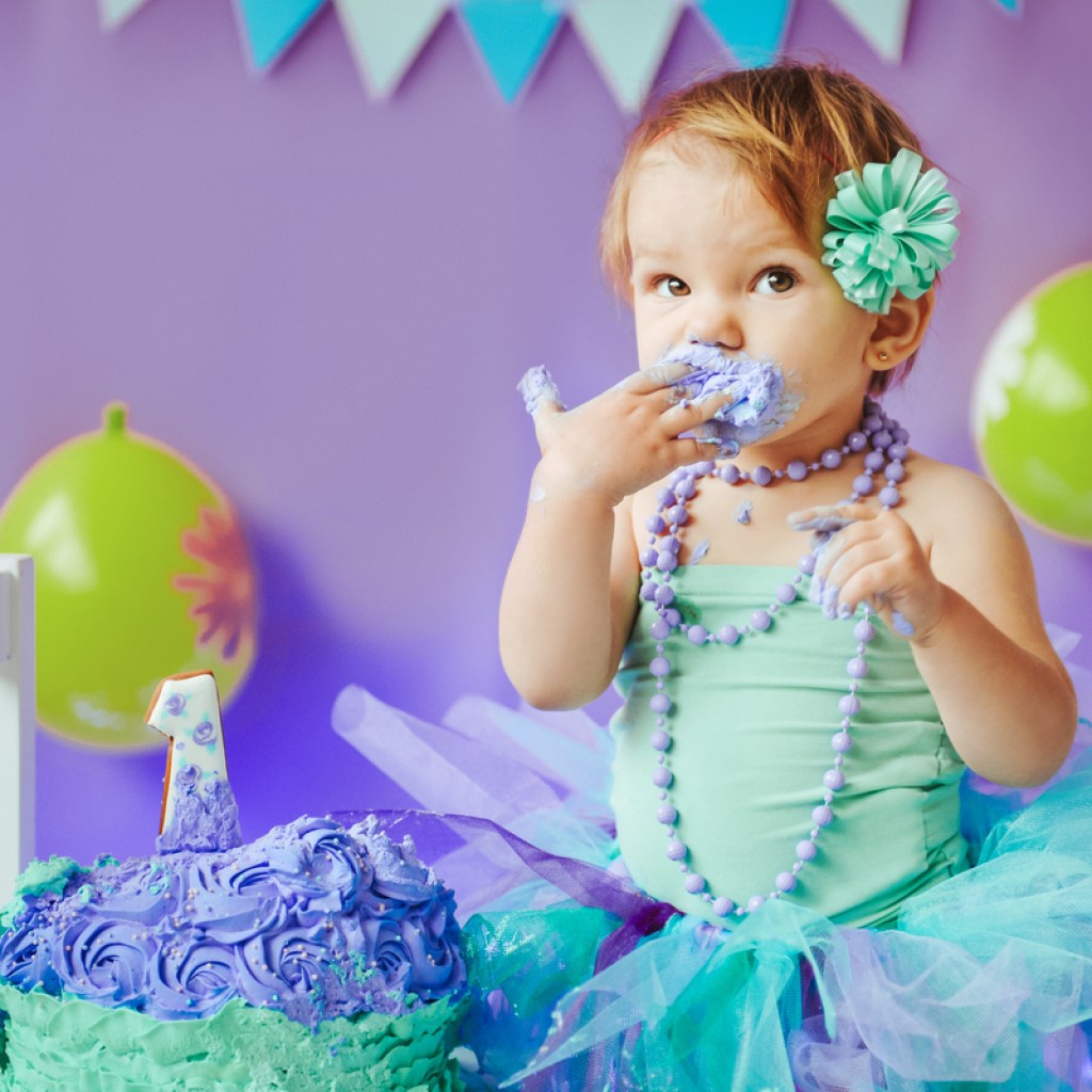 Baby girl enjoying her smash cake on her first birthday