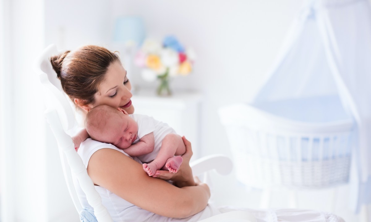 Mom sitting and rocking sleeping baby.