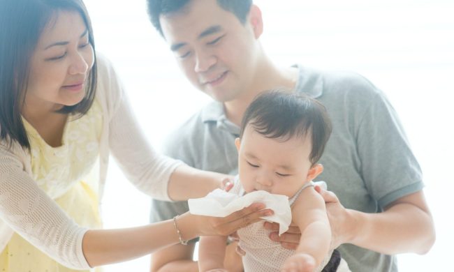 Parents cleaning a baby's face.