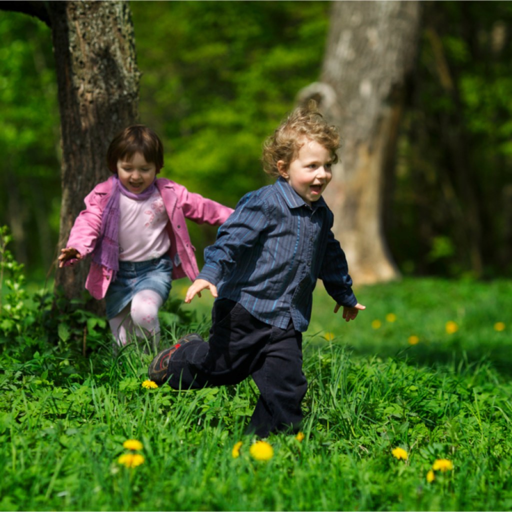 Toddler girl and boy having fun running in the park