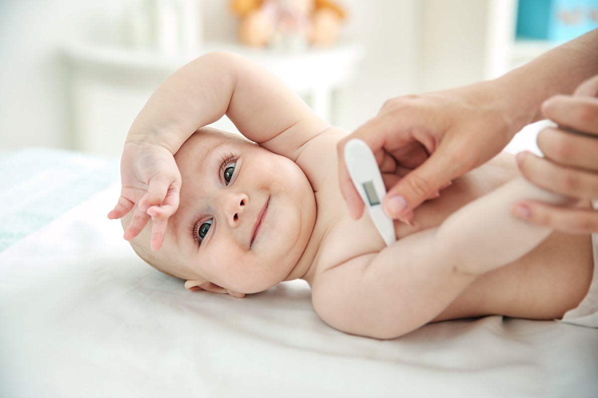 Baby in bed with a thermometer