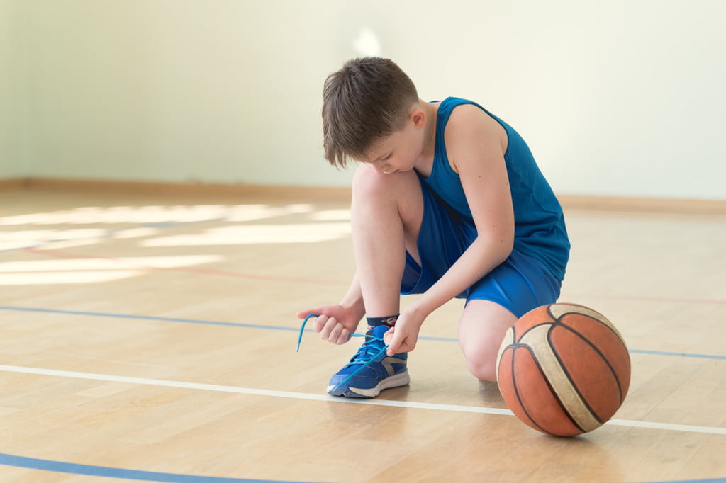 Boy playing basketball and tying his shoes