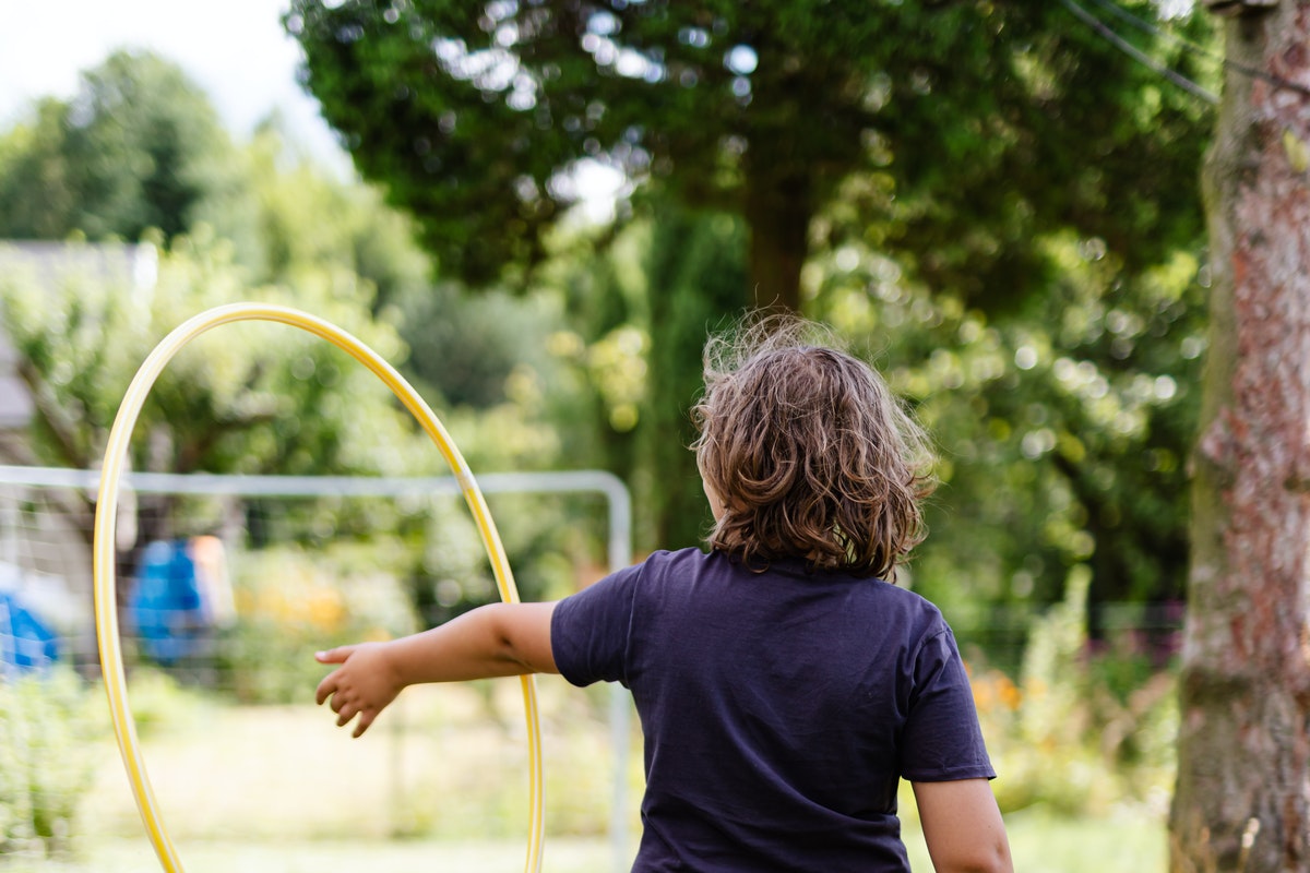 A boy playing with a hula hoop in a backyard