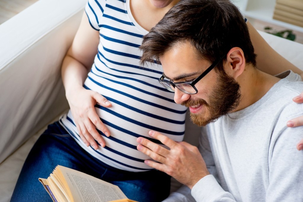 A dad reading to baby in mom's belly.