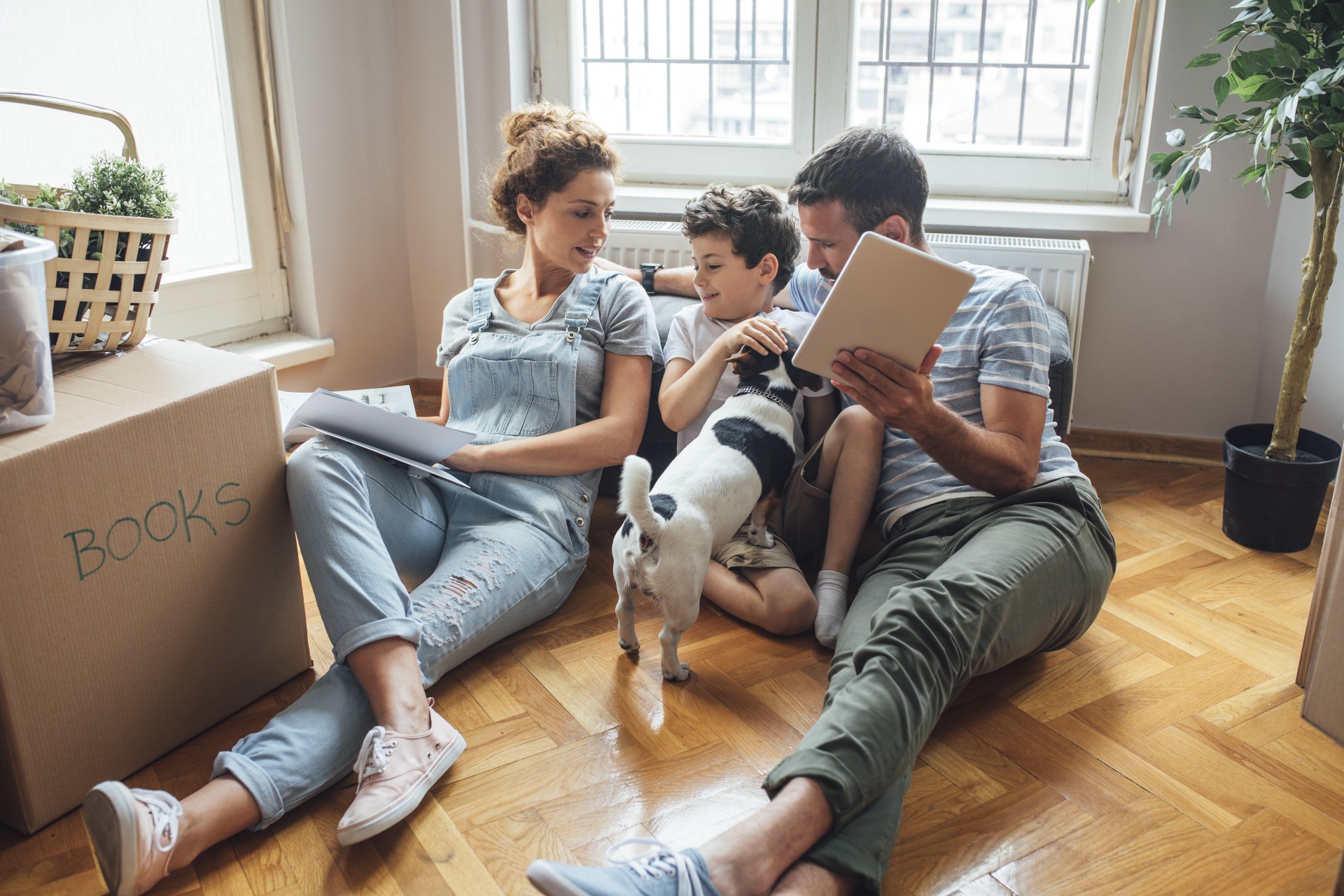 Family with a dog sitting on wooden floor.