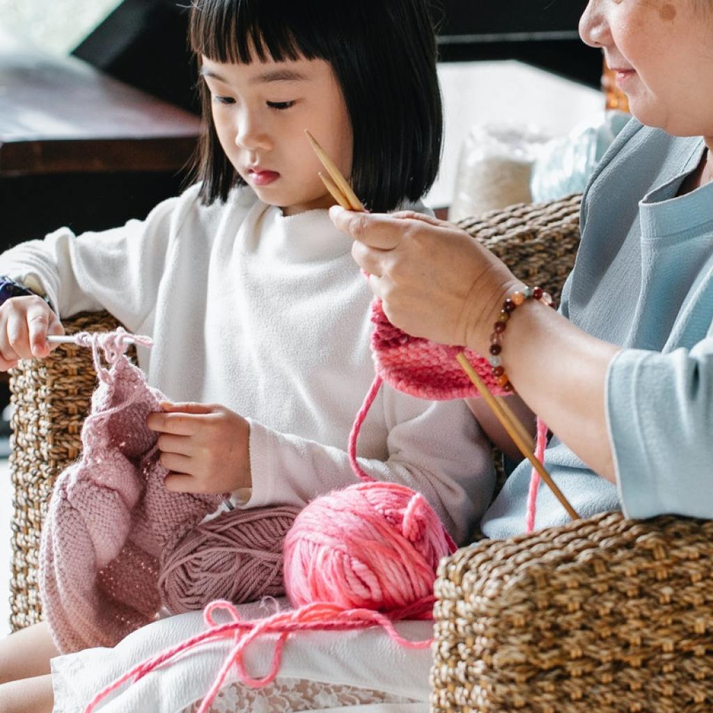 girl learning how to knit with her mother