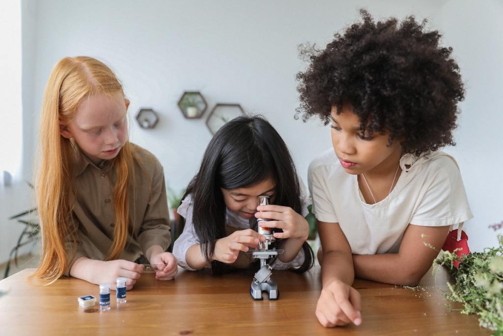 Three young girls using a microscope