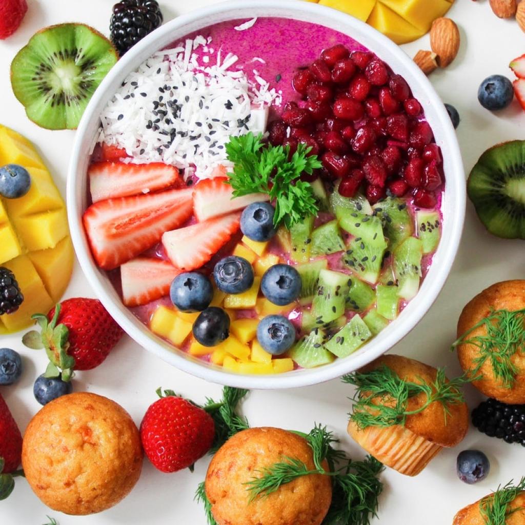 Fruits in a bowl and on a table with muffins