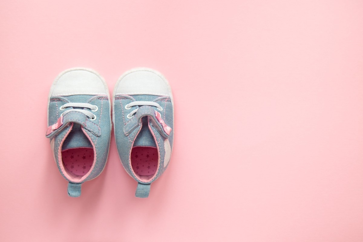 A pair of baby shoes on a pink floor