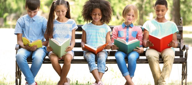 Five kids reading books on a park bench