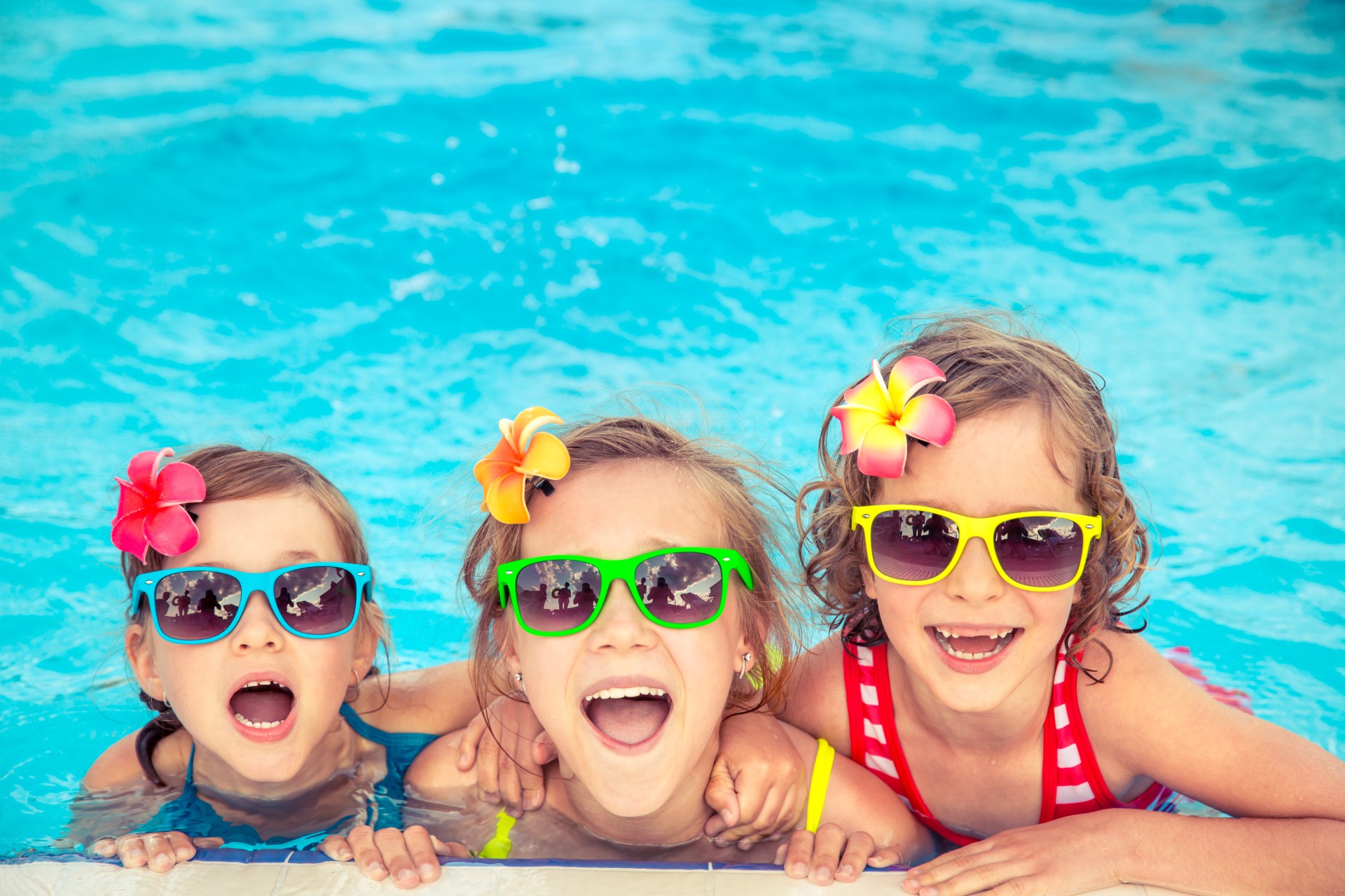Kids having fun in a pool and wearing sunglasses.