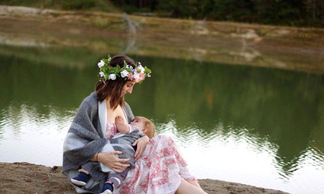 Mom breastfeeding baby near a river