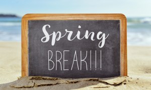 Chalkboard sign saying "spring break" on a beach