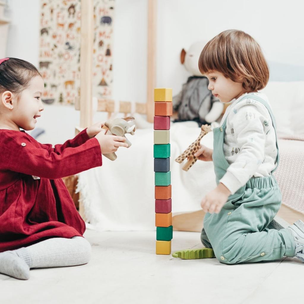 Two toddlers playing with blocks