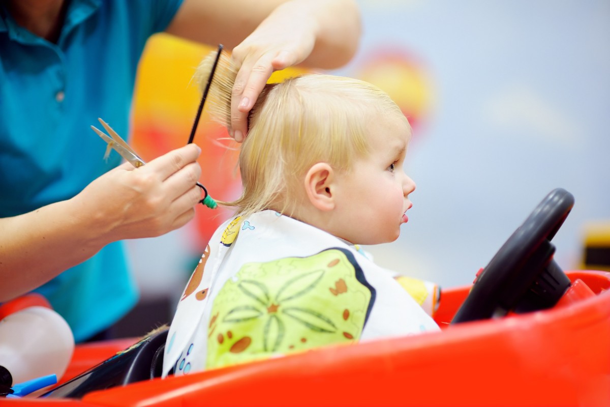 A baby getting a haircut in a salon ride-on chair.