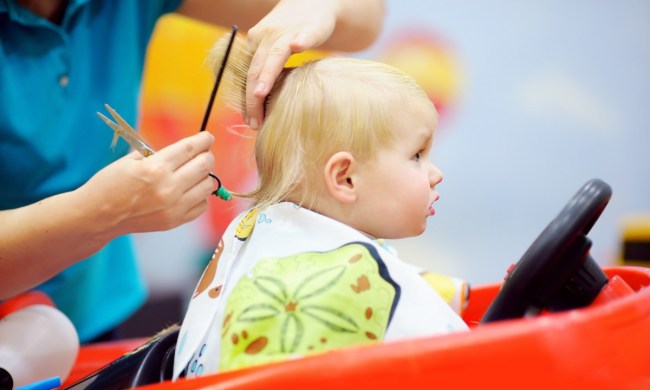 A baby getting a haircut in a salon ride-on chair