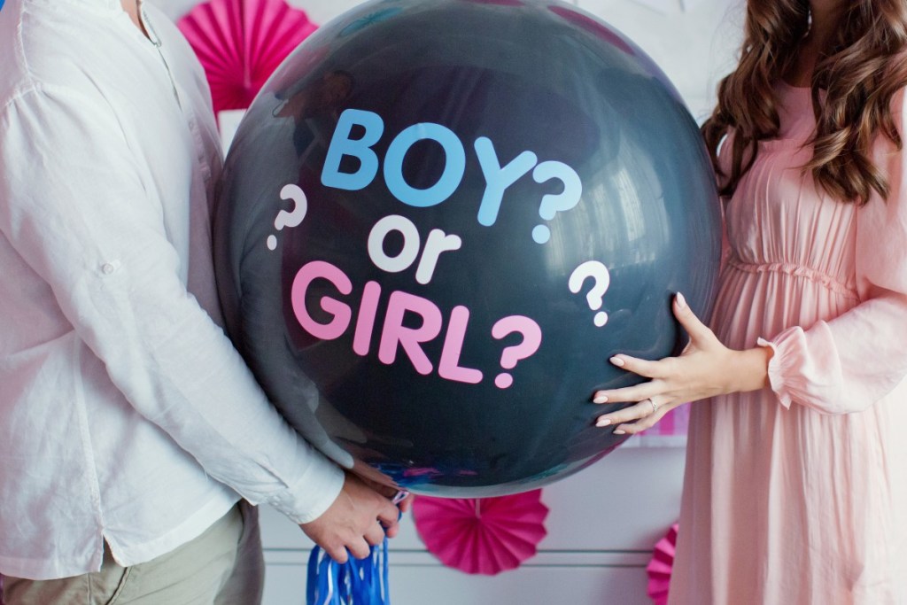 A couple holding a gender-reveal balloon