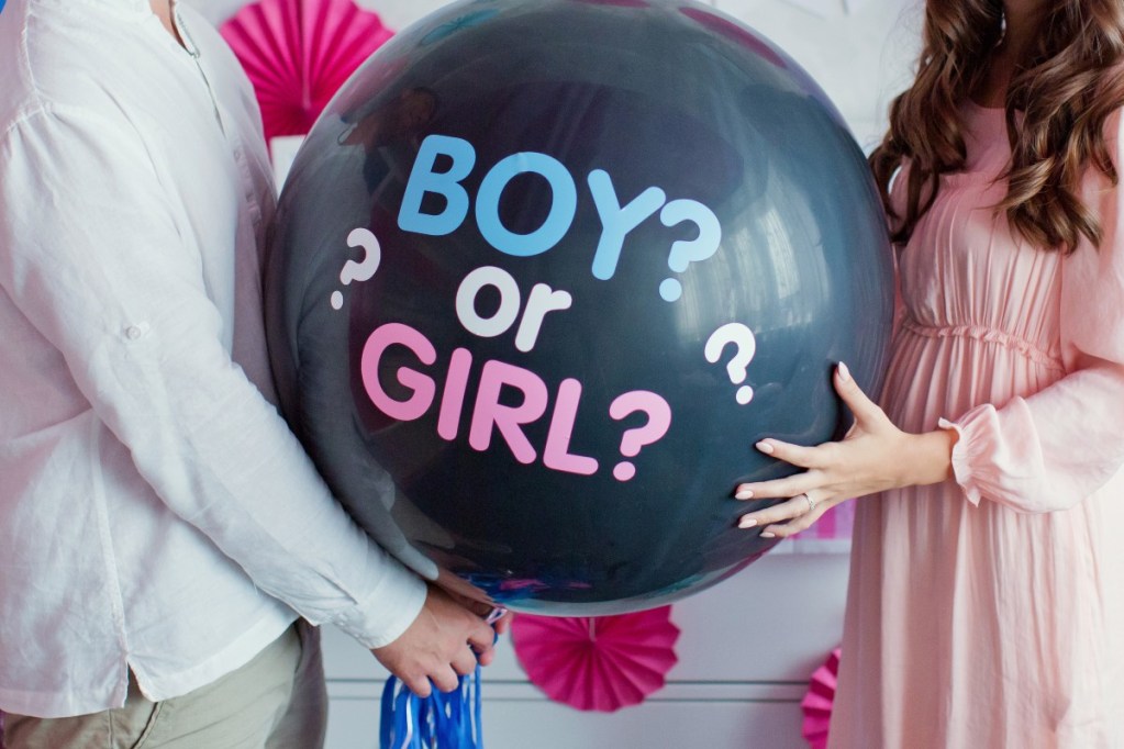 A couple holding a gender reveal balloon