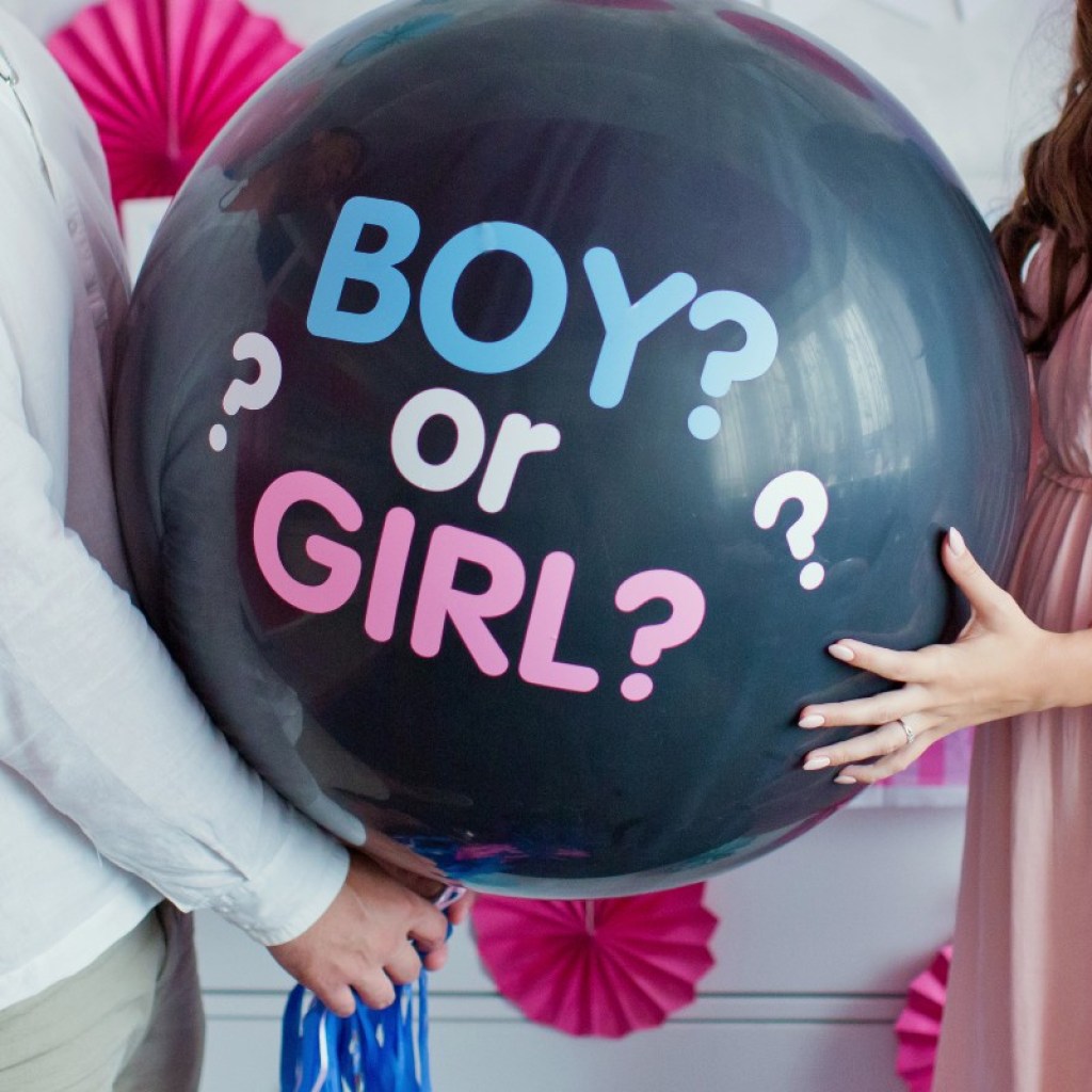 A couple holding a gender-reveal balloon