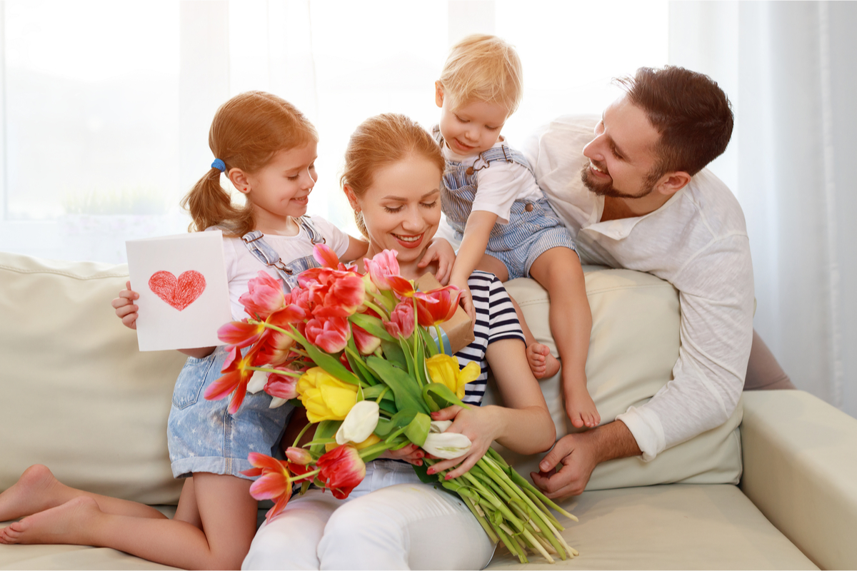 Family giving Mom flowers and a card for Mother's Day