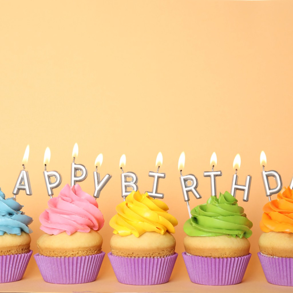 Happy birthday cupcakes in a row with candles