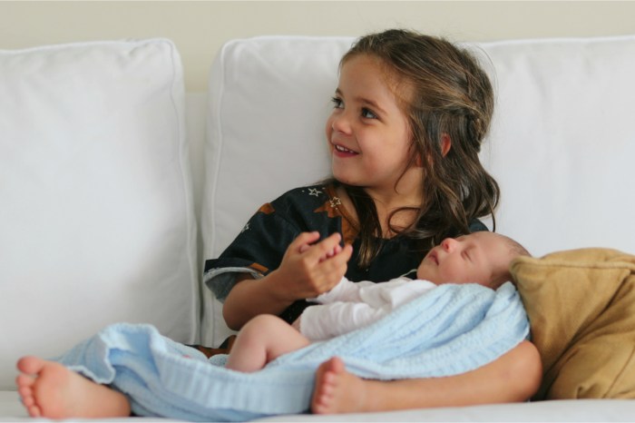 Little girl holding her newborn sibling
