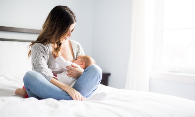 Mom breastfeeding baby on bed.