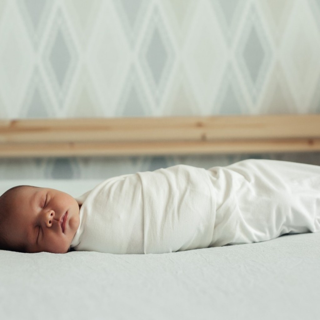 Swaddled sleeping baby in a bed
