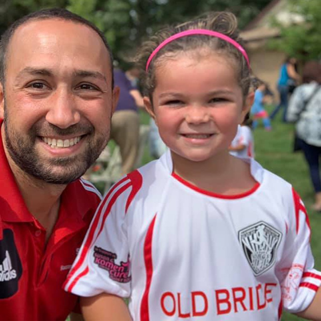Coach Will Gould and smiling youth soccer player