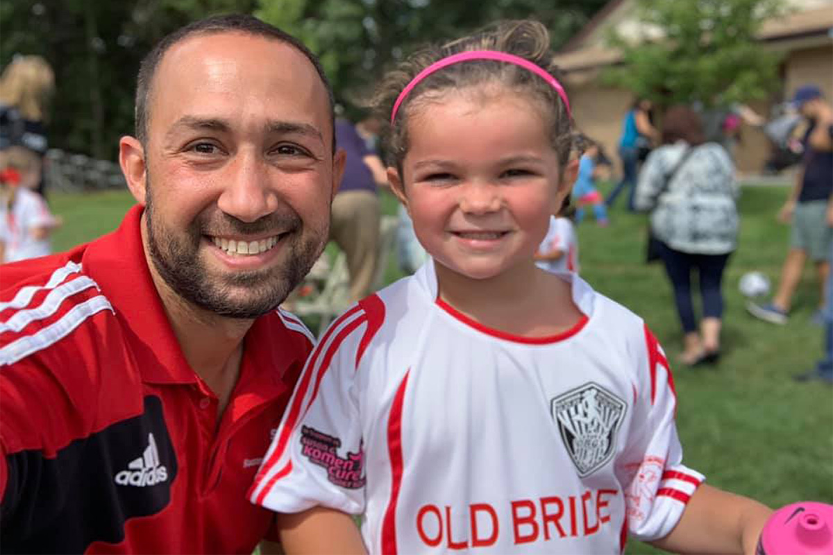 Coach Will Gould and smiling youth soccer player