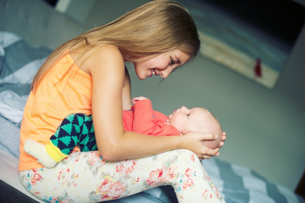Teenage girl holding baby sibling.