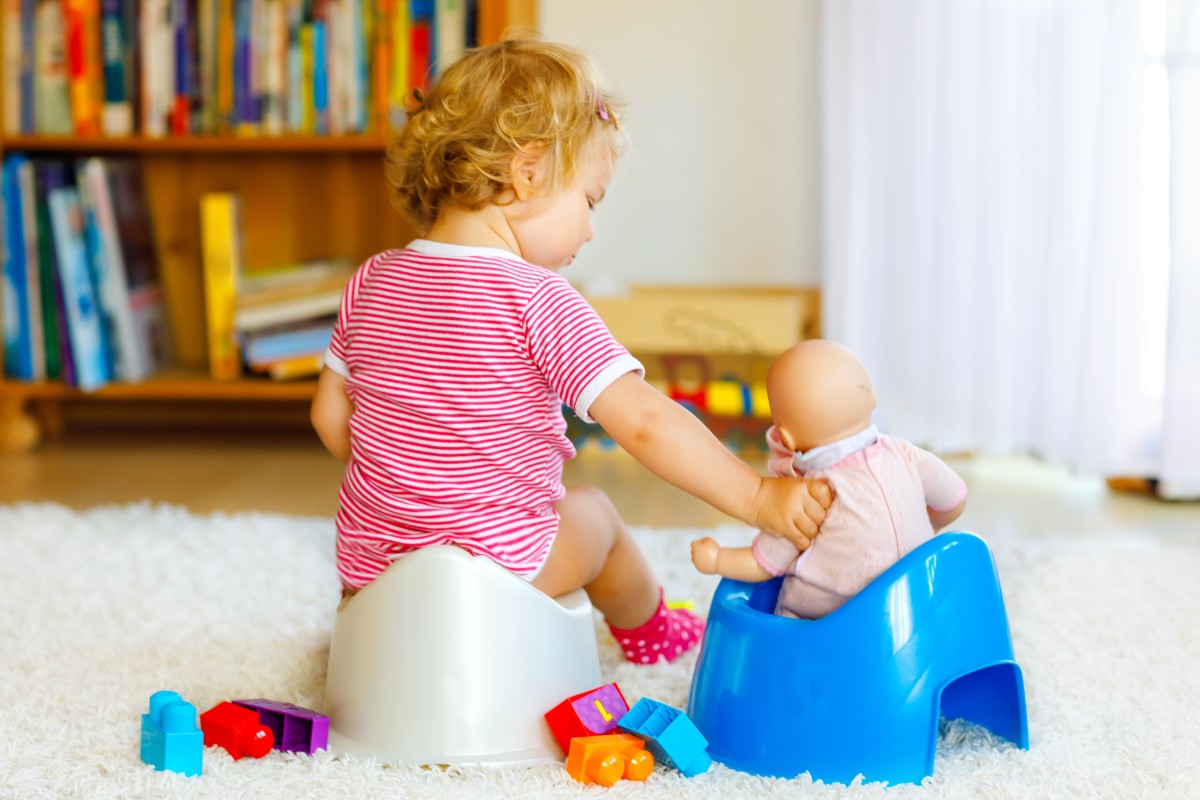 A toddler potty training with doll.