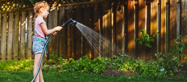 Young kid watering the garden outdoors