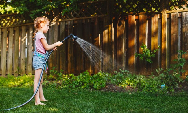 Young kid watering the garden outdoors