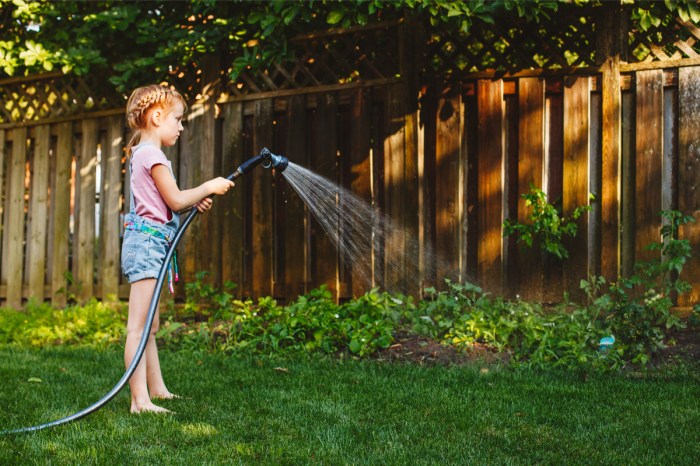 Young kid watering the garden outdoors