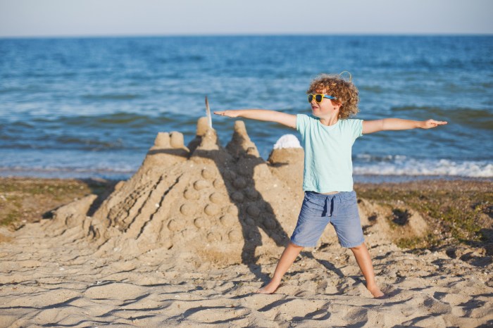 kids beach activities boy posing by sandcastle