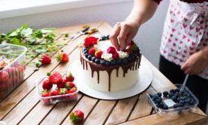 Cake being decorated with chocolate and fruit