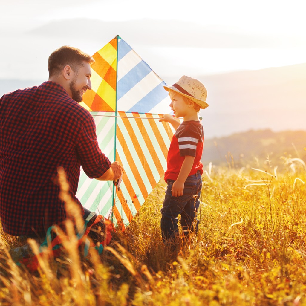 father and son having fun flying a kite in a field
