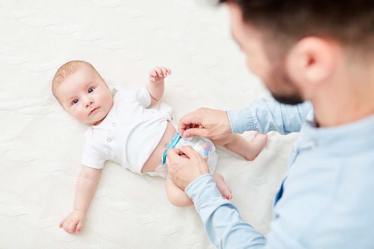 A dad making a disposable diaper change on a baby