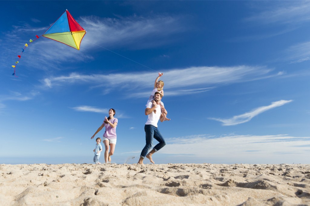 family having fun flying a kite on the beach