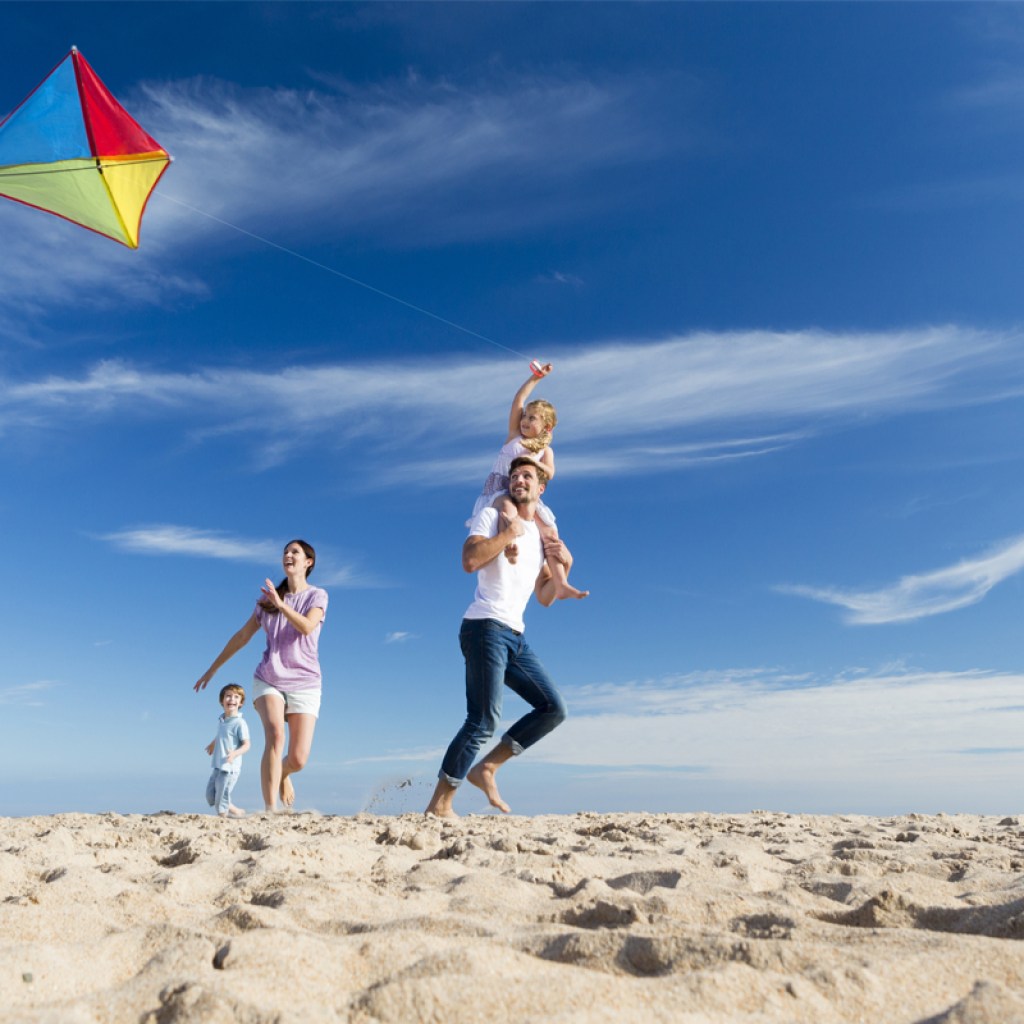 family having fun flying a kite on the beach