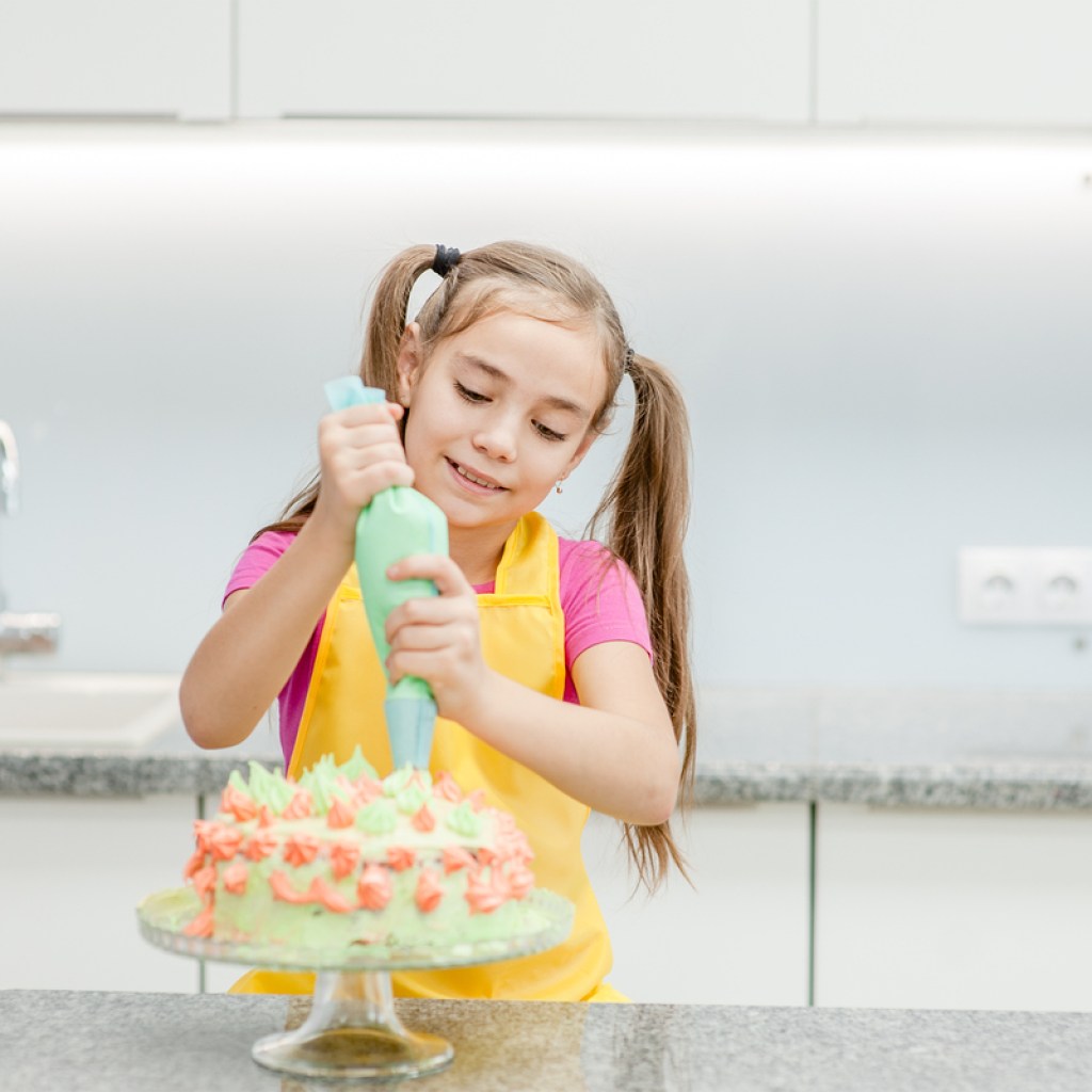 young girl decorating a cake in her kitchen