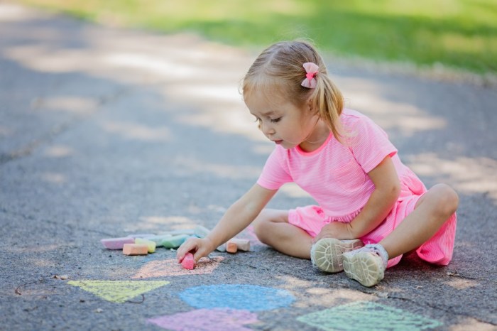 Girl drawing outside with sidewalk chalk